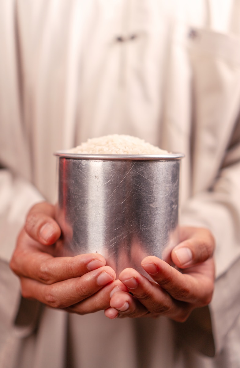 Hands hold a cup filled with white rice.